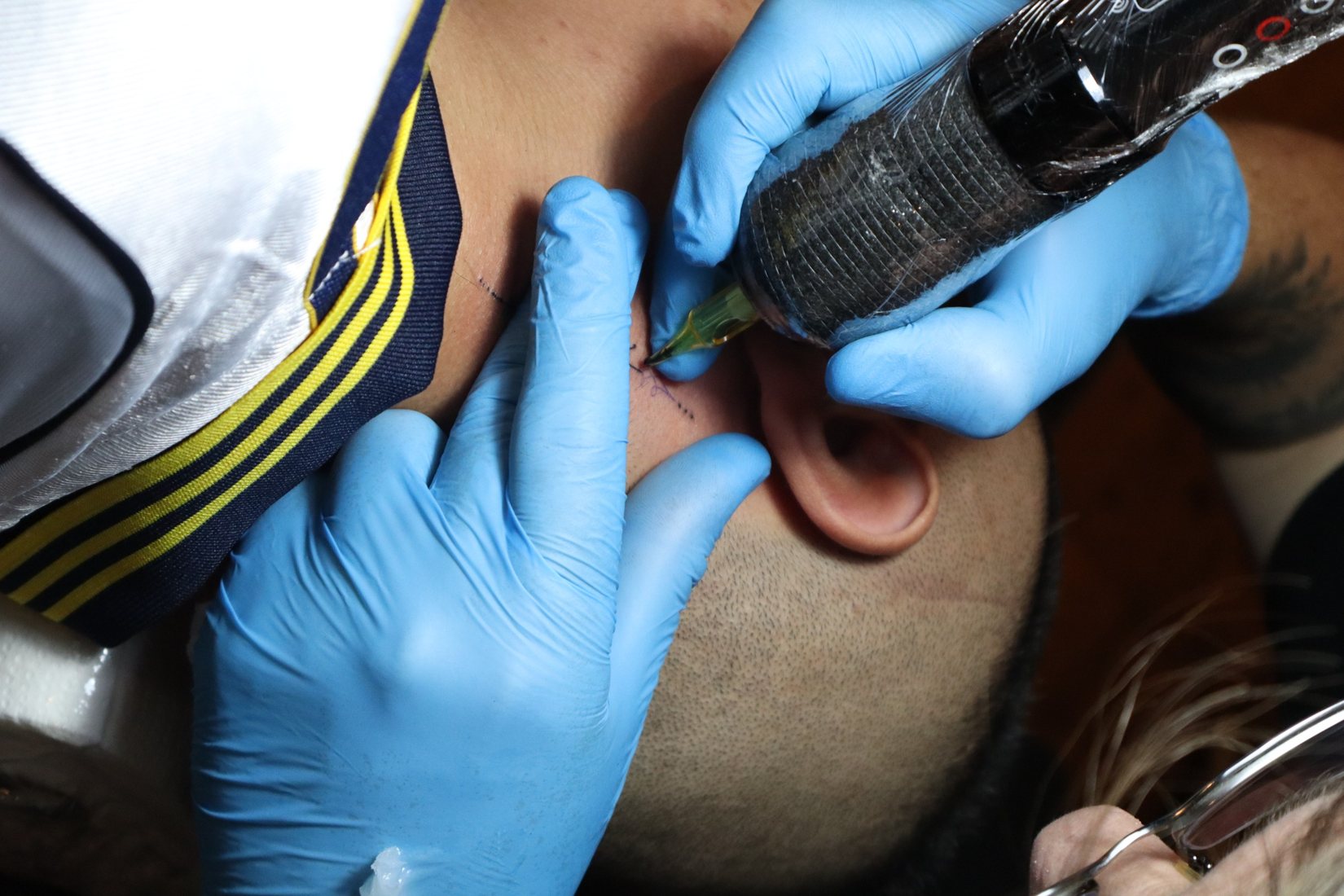 Tatuador de luvas aplicando uma tatuagem