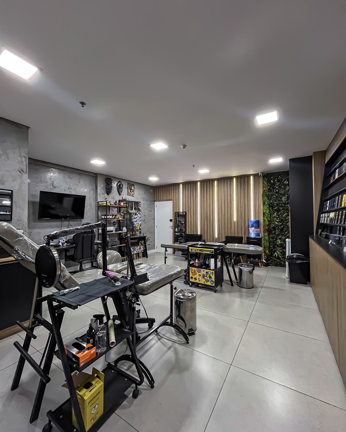 Interior do estúdio Ink Station: macas, parede verde e bancadas
